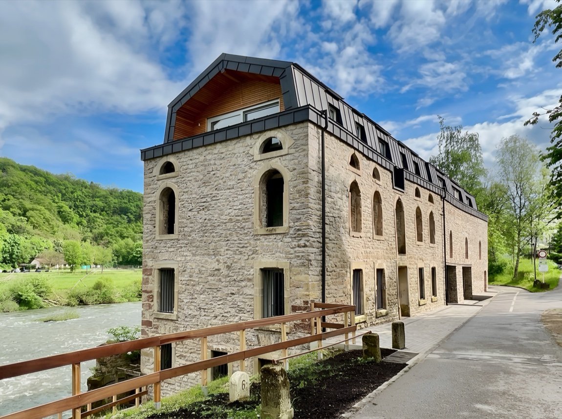 A converted stone mill building beside a river in Luxembourg