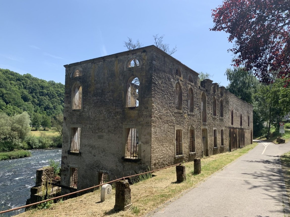 Riverside stone building before renovation, with an open roof and empty window openings